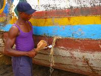 Sierra Leone, repairing a boat (pounding fibers into the cracks)