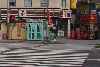 Detail of crosswalk blocked by telephone booth and kiosk.