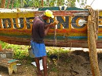 Sierra Leone, repairing a boat (pounding fibers into the cracks)