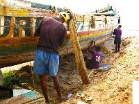 Sierra Leone, repairing a boat (pounding fibers into the cracks)